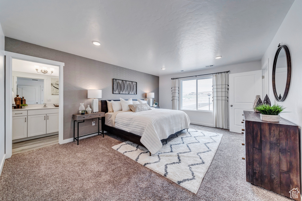 Bedroom featuring baseboards, light carpet, a sink, and ensuite bath