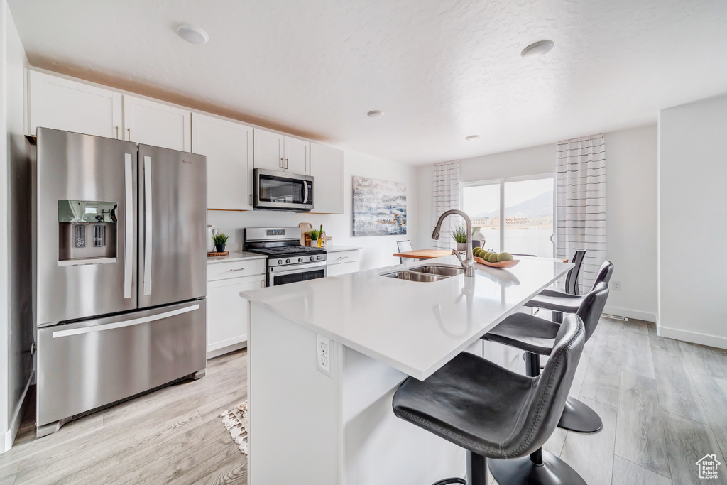 Kitchen with stainless steel appliances, a kitchen breakfast bar, a sink, and a center island with sink