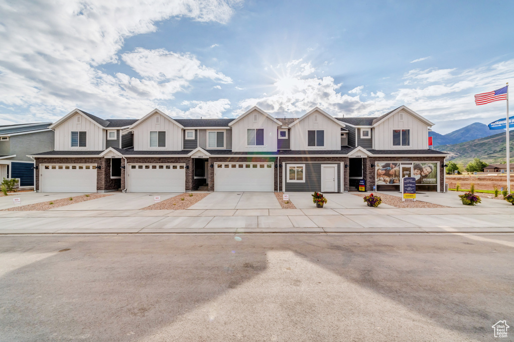 Townhome / multi-family property with concrete driveway, brick siding, board and batten siding, and an attached garage
