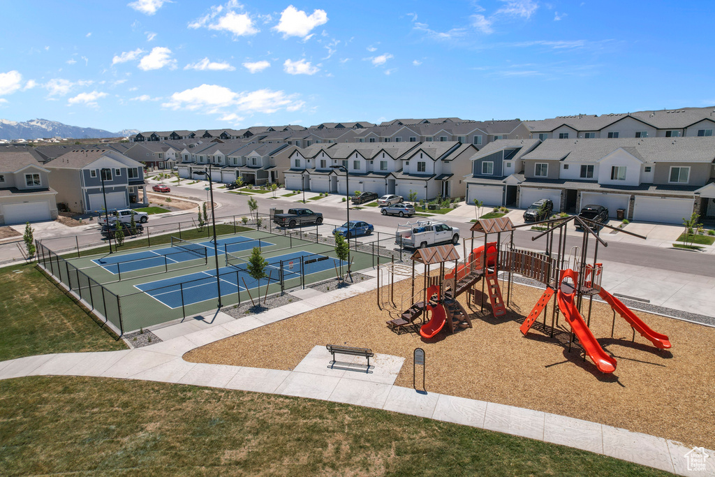 Communal playground with a tennis court, a residential view, and fence