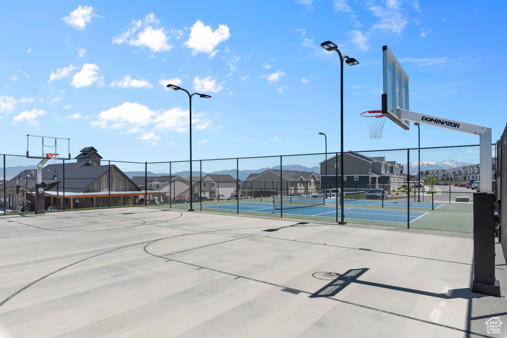 View of sport court featuring a tennis court, community basketball court, fence, and a residential view