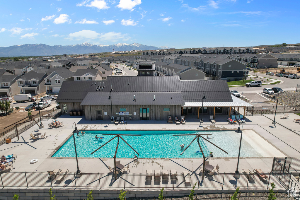 Pool featuring a mountain view, a patio, fence, and a residential view
