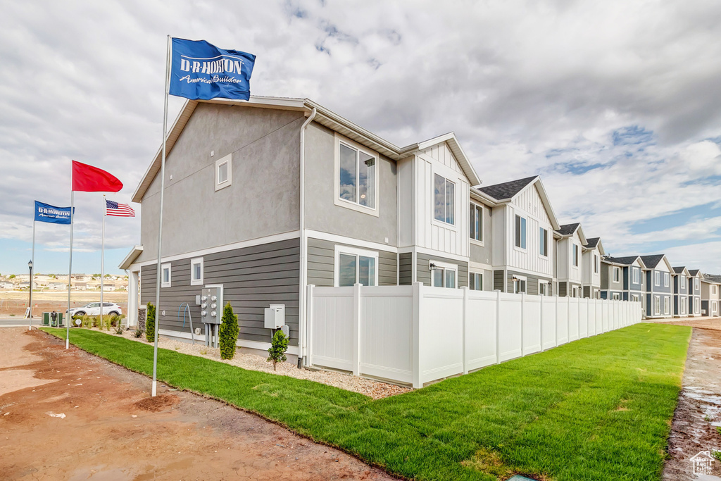 View of side of home with a yard, a residential view, fence, and board and batten siding