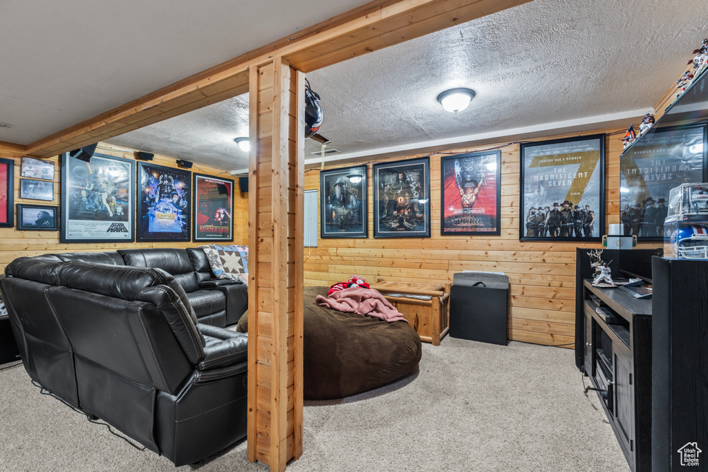 Cinema room featuring carpet floors, wooden walls, and a textured ceiling