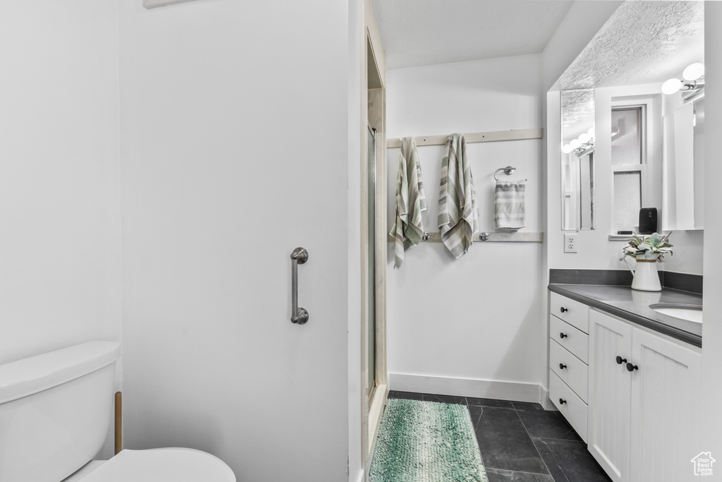 Full bath with toilet, an enclosed shower, vanity, tile patterned flooring, and baseboards