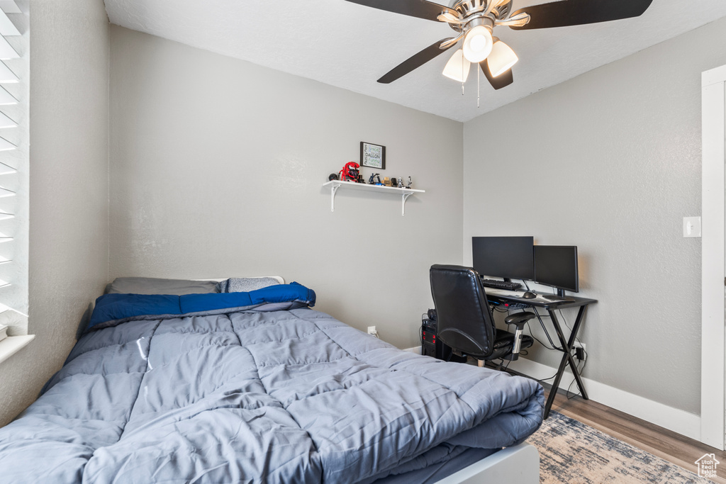 Bedroom featuring wood finished floors, baseboards, and ceiling fan
