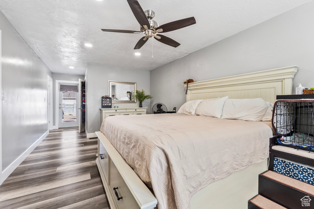 Bedroom featuring dark wood-style flooring, recessed lighting, baseboards, a textured ceiling, and a ceiling fan