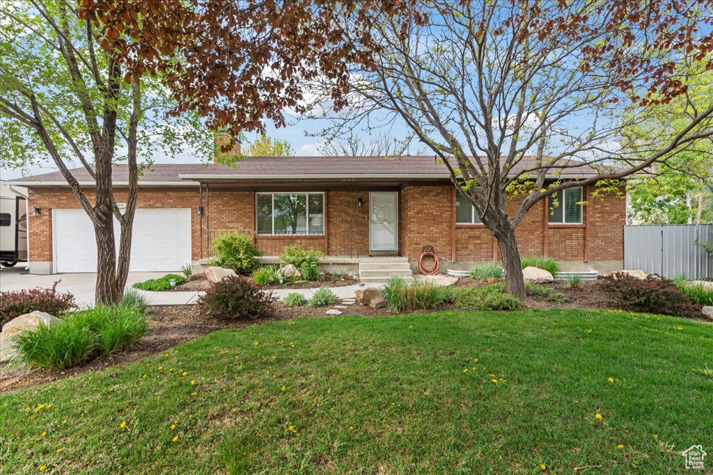 Single story home with driveway, a garage, and brick siding