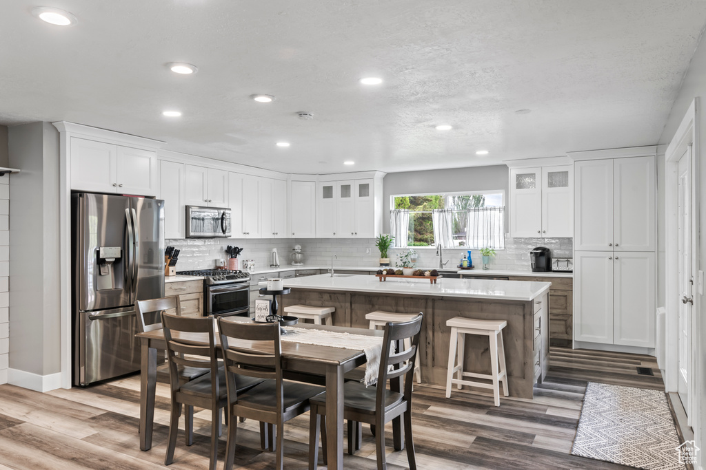 Kitchen featuring appliances with stainless steel finishes, recessed lighting, a kitchen island, backsplash, and light countertops
