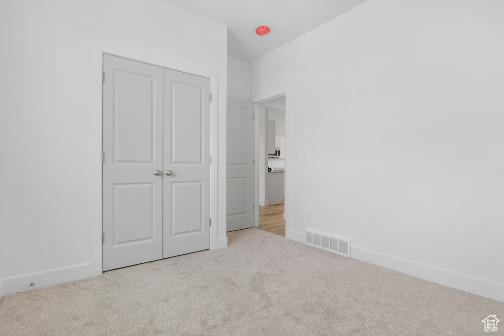 Unfurnished bedroom with light colored carpet and a closet