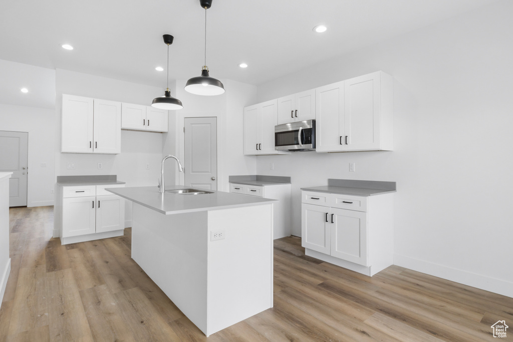 Kitchen with a kitchen island with sink, sink, and white cabinetry