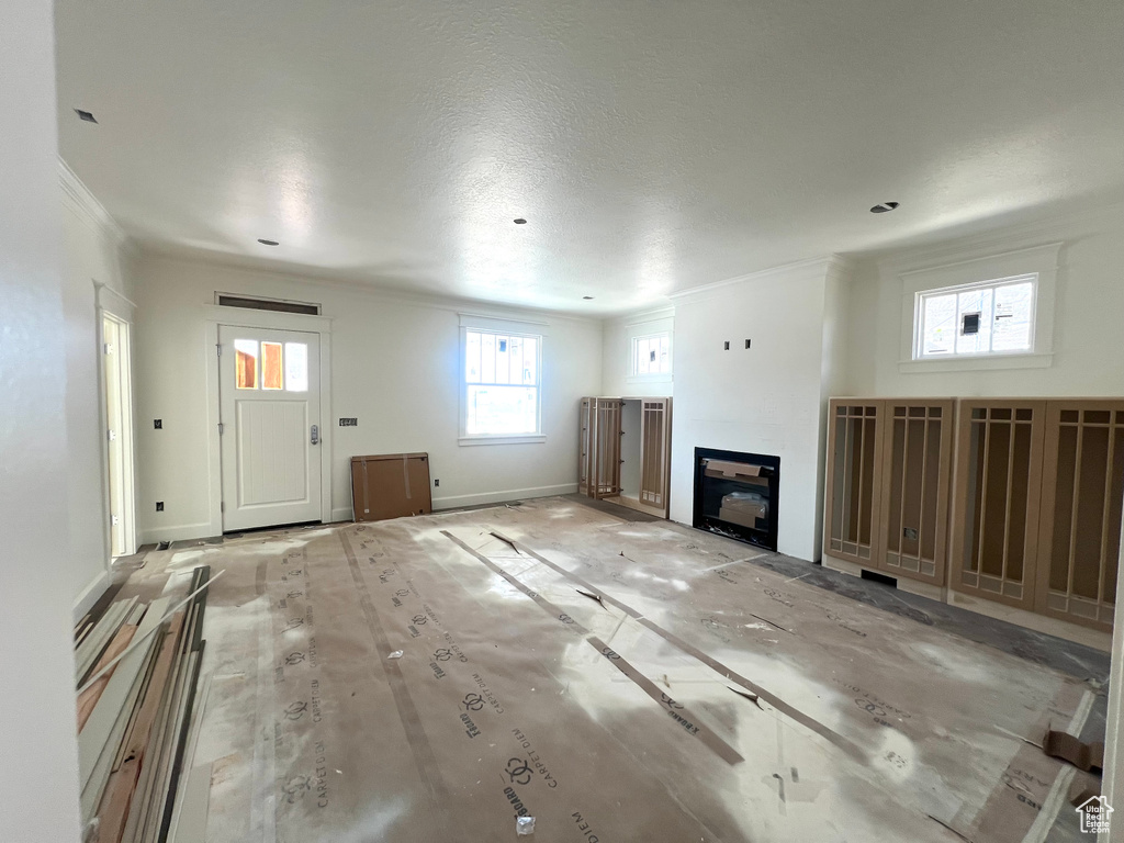 Unfurnished living room featuring ornamental molding and a glass covered fireplace