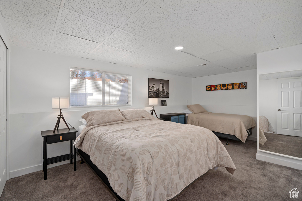 Bedroom featuring carpet, a paneled ceiling, and baseboards
