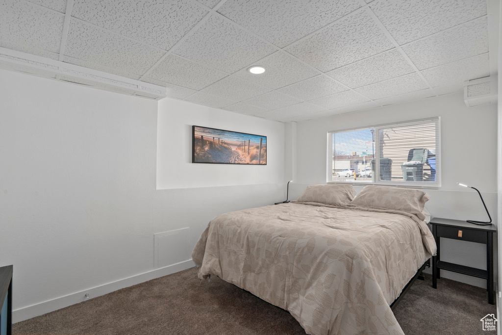 Carpeted bedroom with a paneled ceiling and baseboards