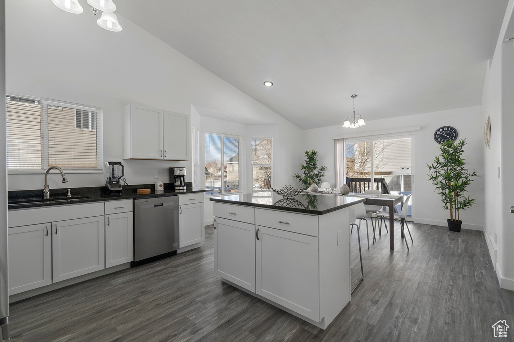 Kitchen featuring dark countertops, stainless steel dishwasher, an inviting chandelier, vaulted ceiling, and a sink