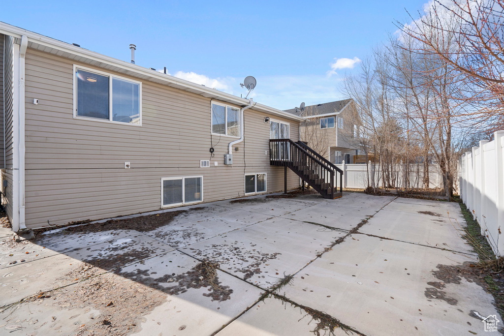 Back of property featuring fence, stairway, and a patio