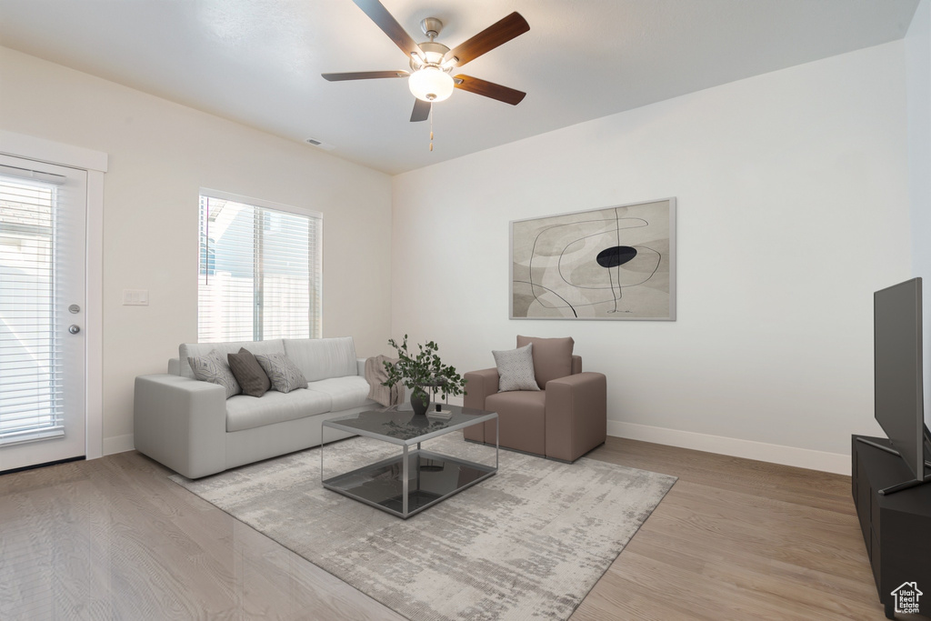 Living area with a ceiling fan, healthy amount of natural light, and wood finished floors