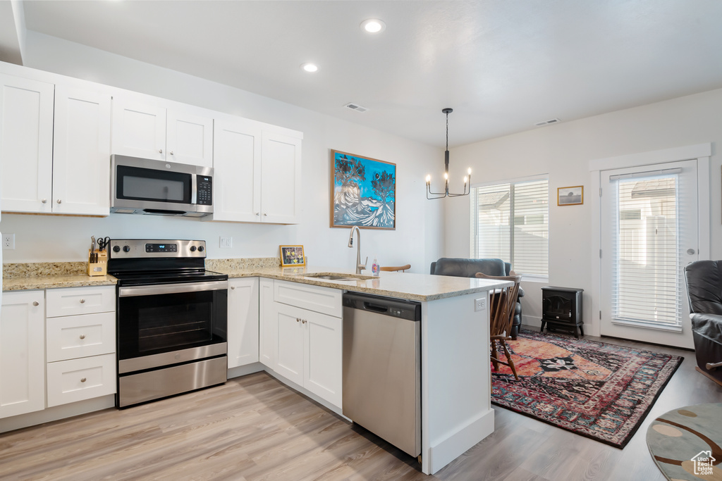 Kitchen with a peninsula, a sink, visible vents, appliances with stainless steel finishes, and a wood stove