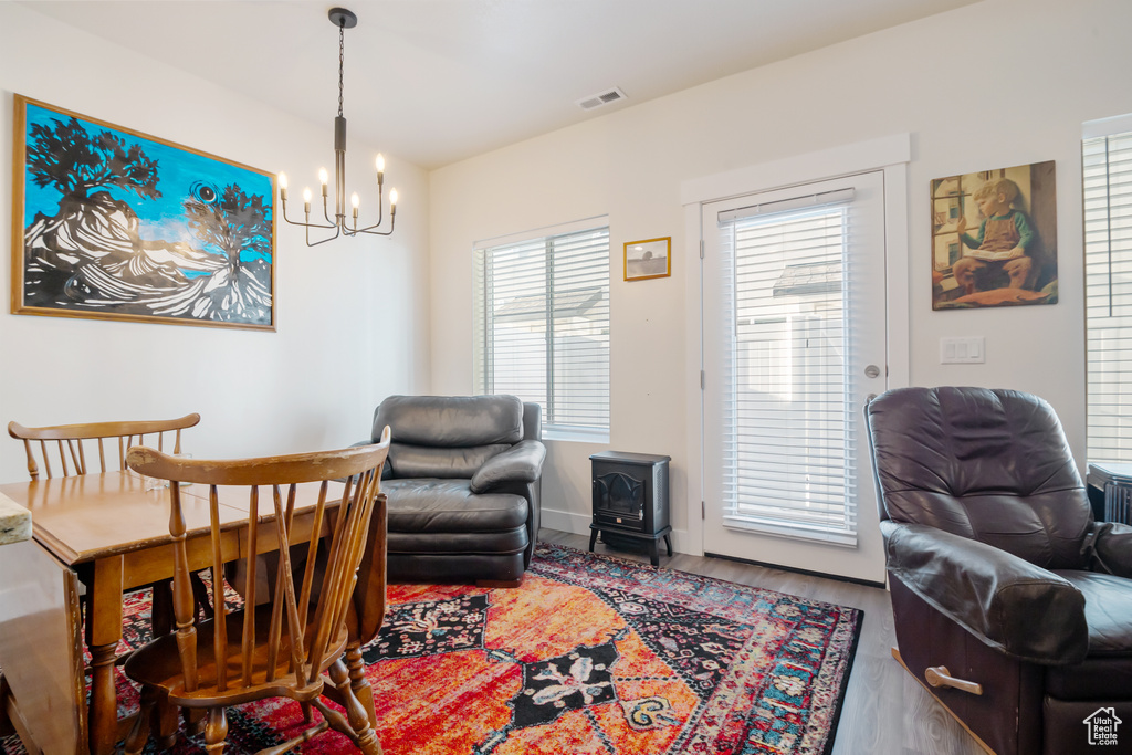 Interior space featuring visible vents, an inviting chandelier, a wood stove, wood finished floors, and baseboards