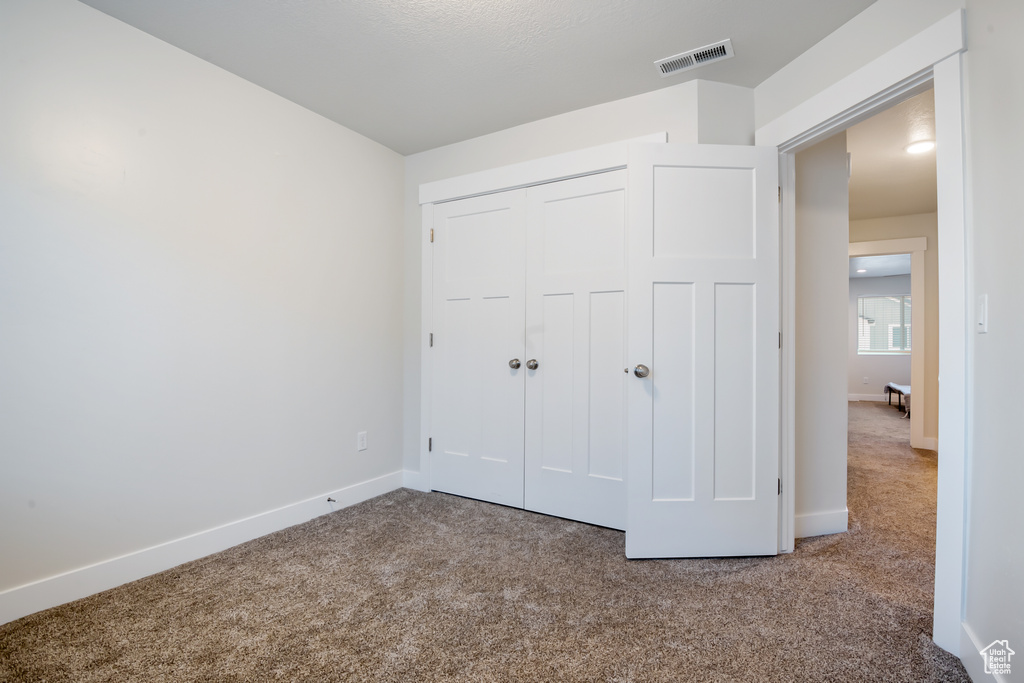 Unfurnished bedroom with carpet, a closet, visible vents, and baseboards