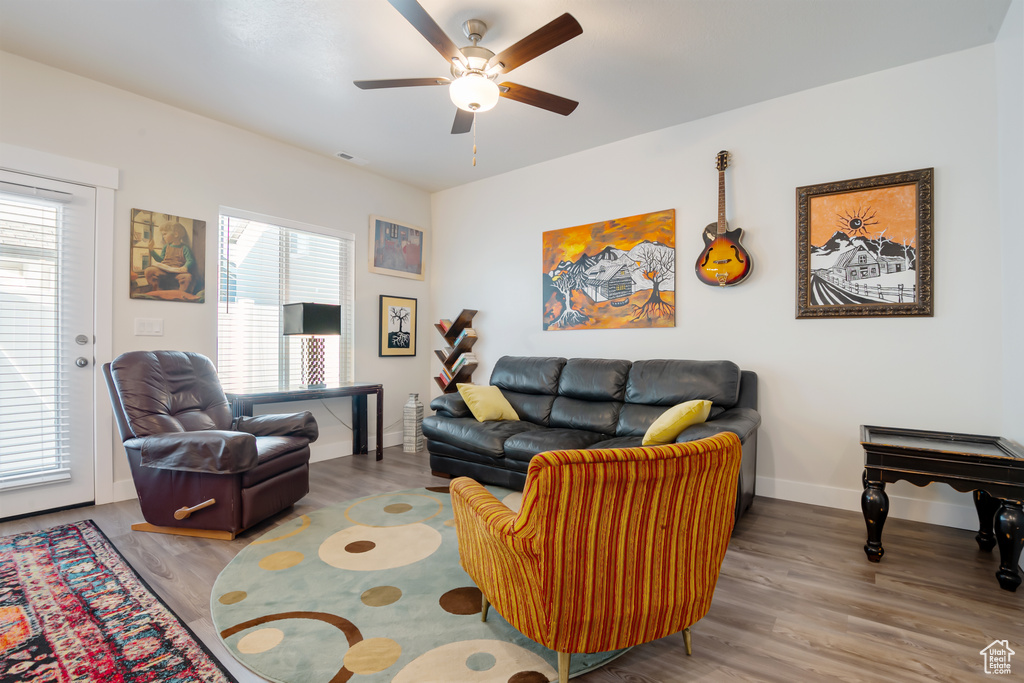 Living room with a ceiling fan, baseboards, and wood finished floors