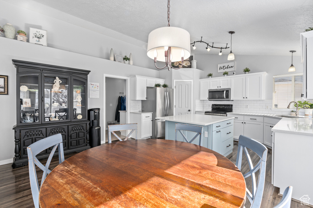 Dining space featuring dark wood-style floors, a chandelier, vaulted ceiling, and a textured ceiling