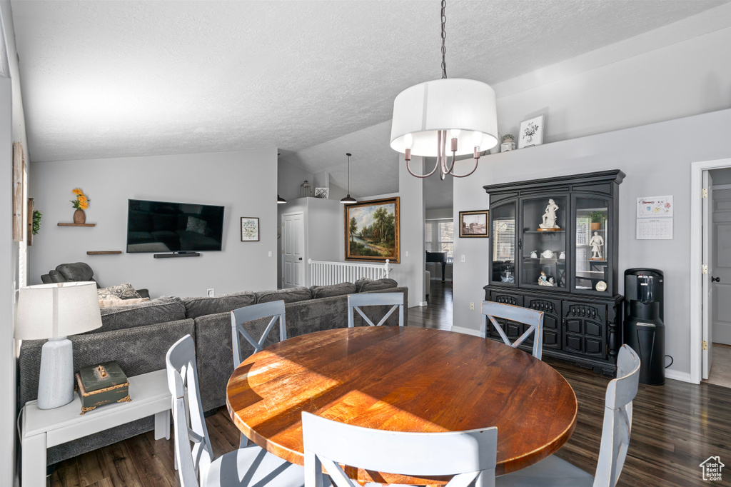 Dining space with lofted ceiling, a textured ceiling, wood finished floors, baseboards, and radiator