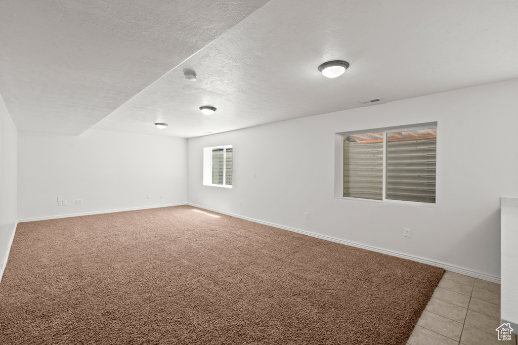 Spare room featuring baseboards, a textured ceiling, and light tile patterned floors