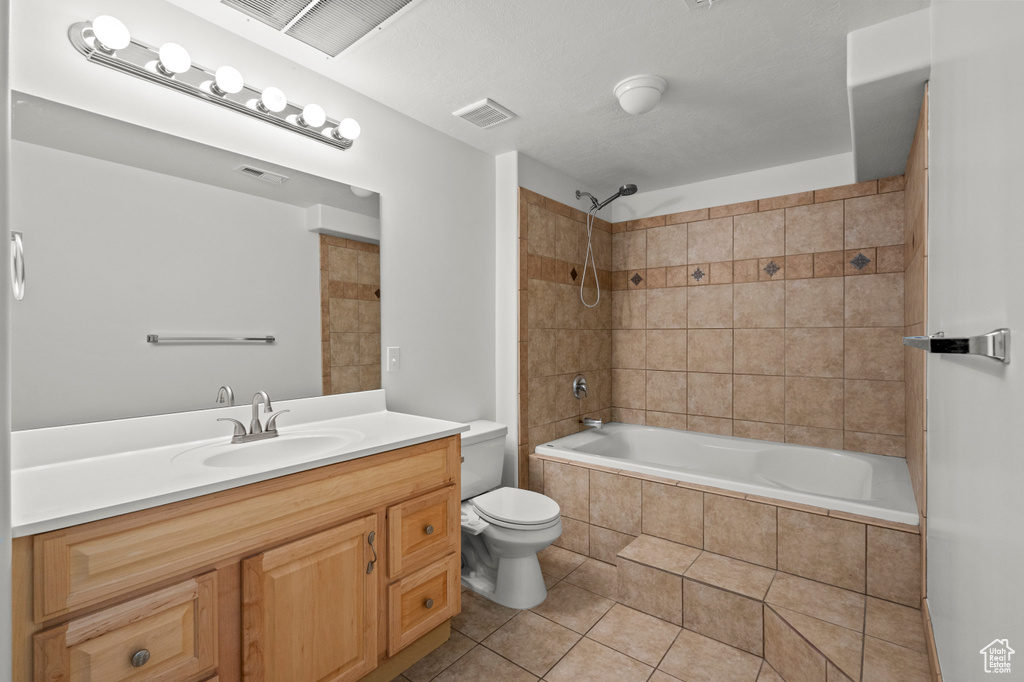 Full bath with toilet, tile patterned floors, tiled shower / bath combo, and vanity