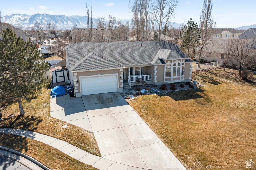 View of front of house with roof with shingles, a porch, concrete driveway, a garage, and a front lawn