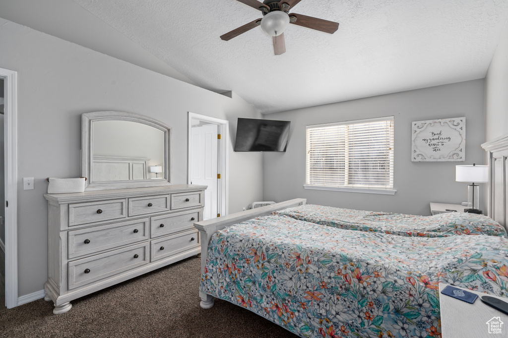Bedroom with lofted ceiling, dark carpet, a ceiling fan, a textured ceiling, and baseboards
