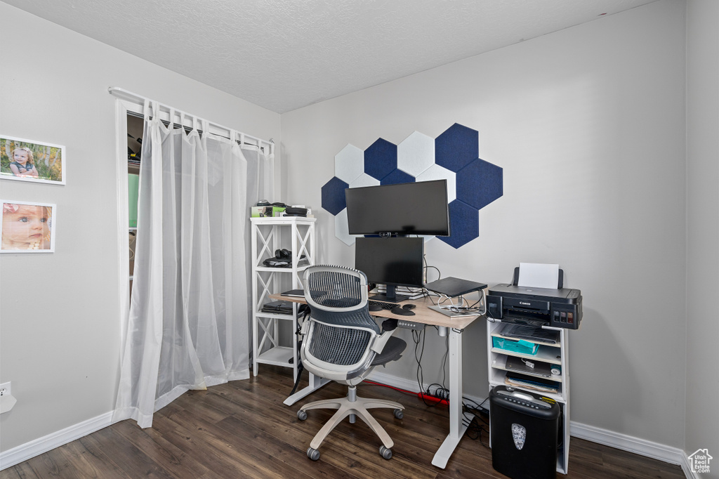 Home office featuring a textured ceiling, baseboards, and wood finished floors