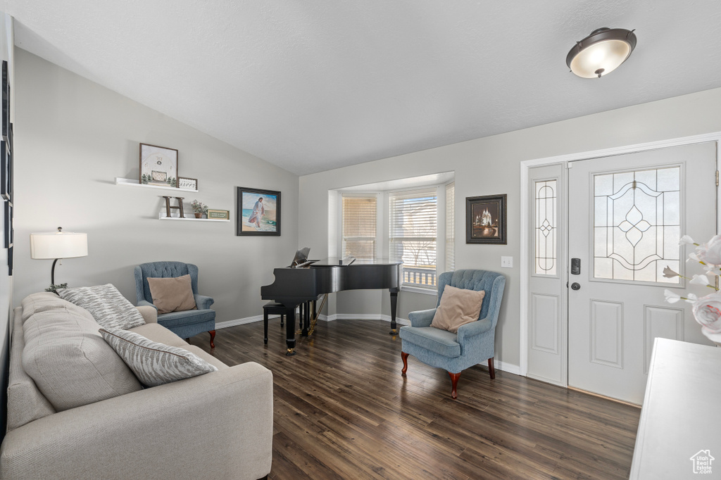 Living room with dark wood-type flooring, lofted ceiling, and baseboards
