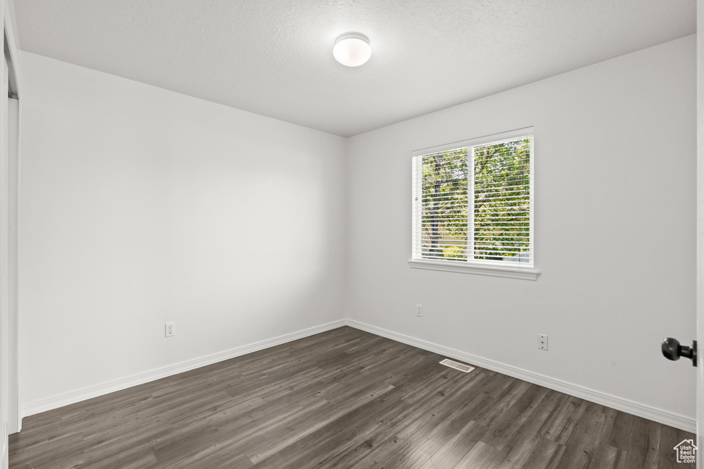 Unfurnished room featuring dark wood-type flooring and baseboards