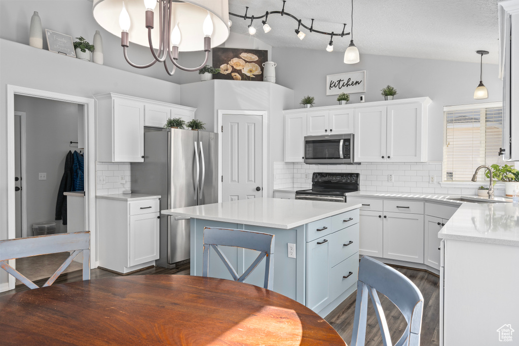 Kitchen featuring vaulted ceiling, stainless steel appliances, a sink, and light countertops
