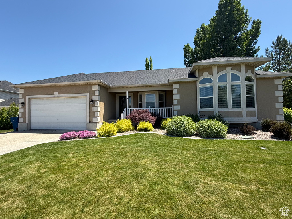 View of front of home with stucco siding, a garage, a front lawn, and driveway