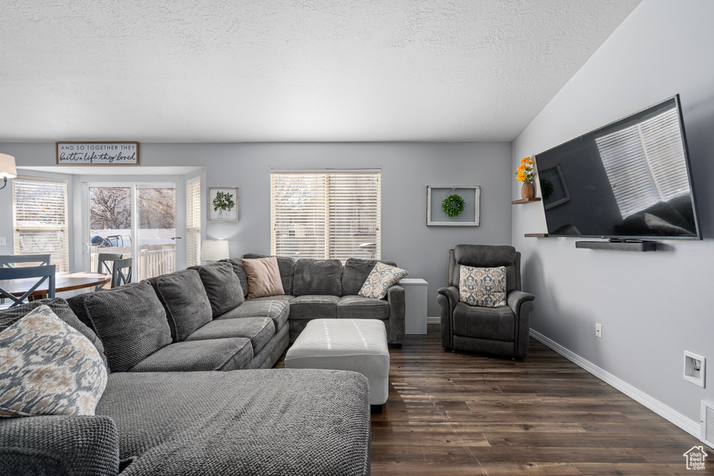Living room featuring dark wood-type flooring, a textured ceiling, and baseboards