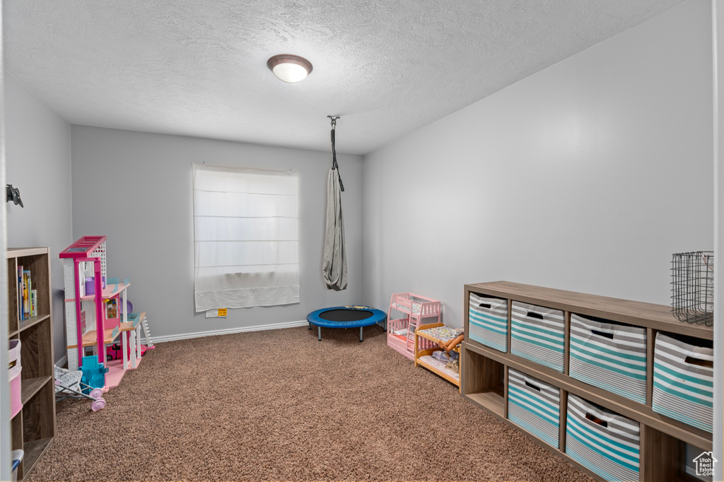 Playroom featuring carpet flooring, a textured ceiling, and baseboards