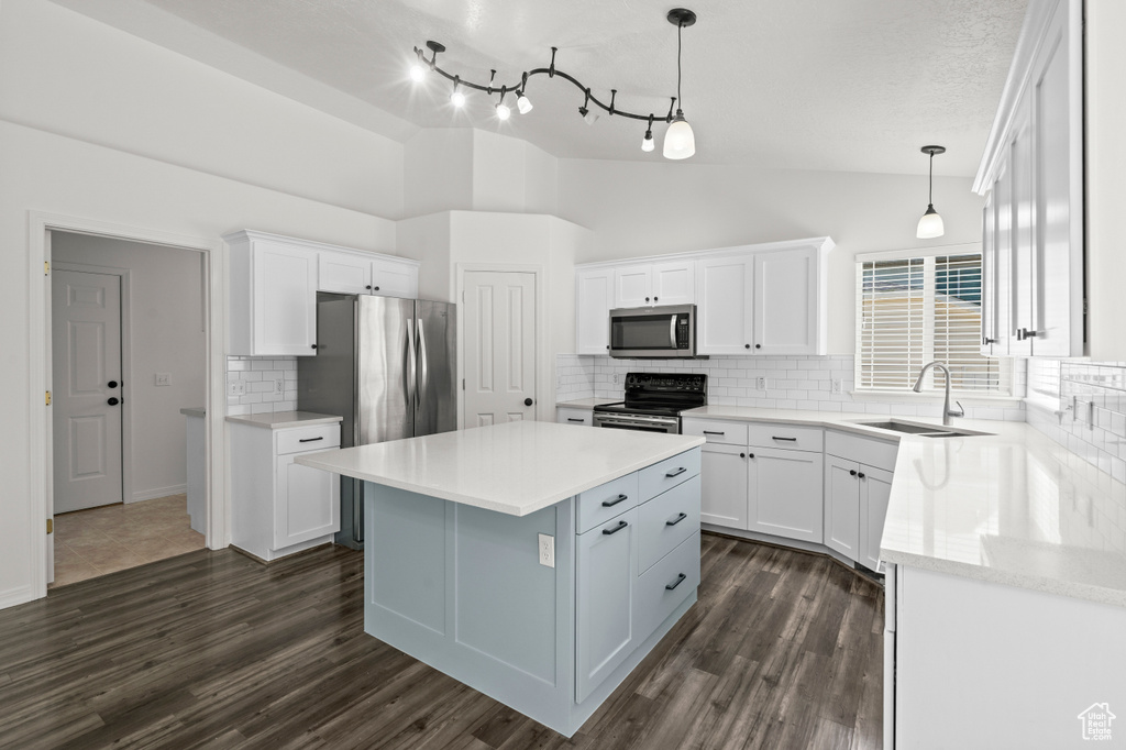 Kitchen with stainless steel appliances, a sink, white cabinets, a center island, and dark wood finished floors