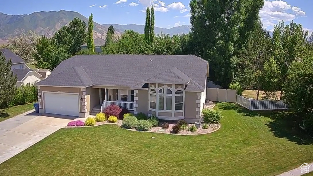 View of front of home with an attached garage, stucco siding, concrete driveway, a porch, and a mountain view