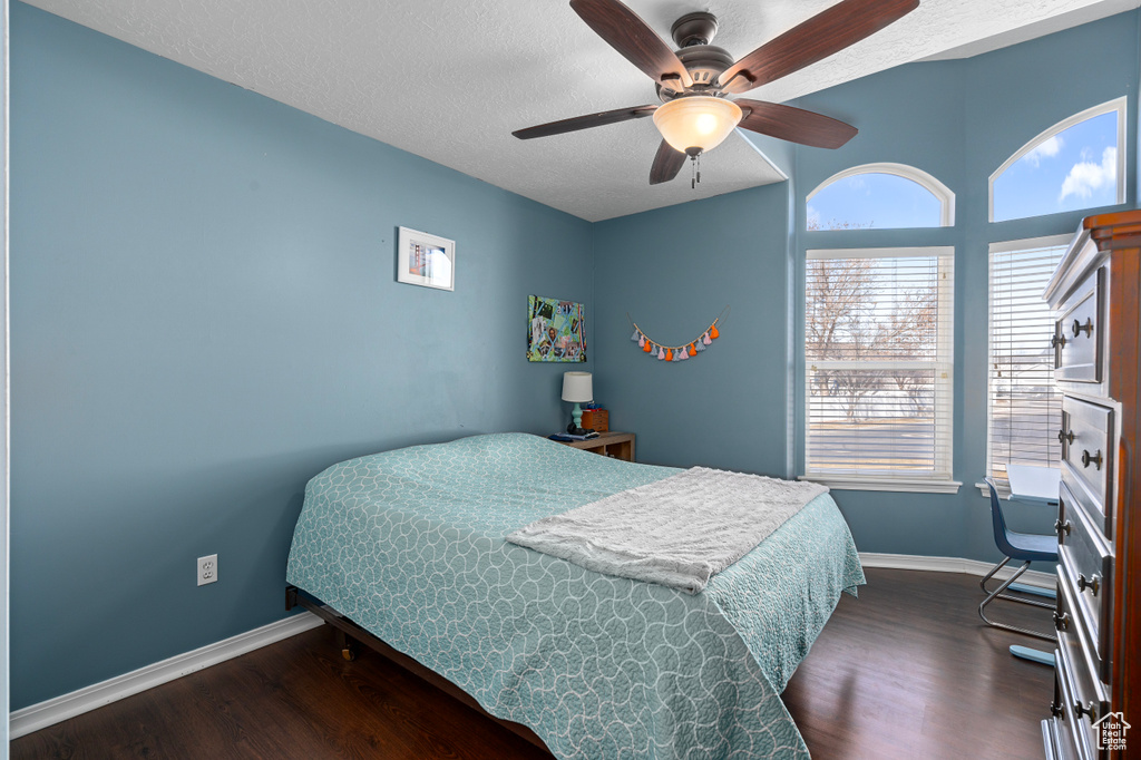 Bedroom with dark wood-type flooring, a textured ceiling, and baseboards