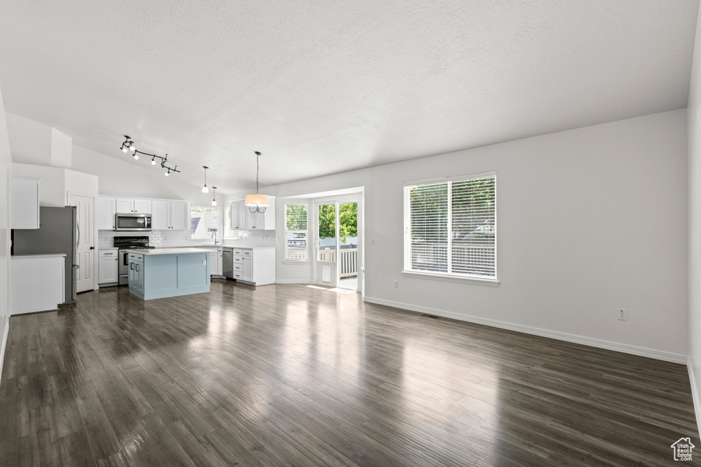 Unfurnished living room with dark wood-style floors, baseboards, and a textured ceiling