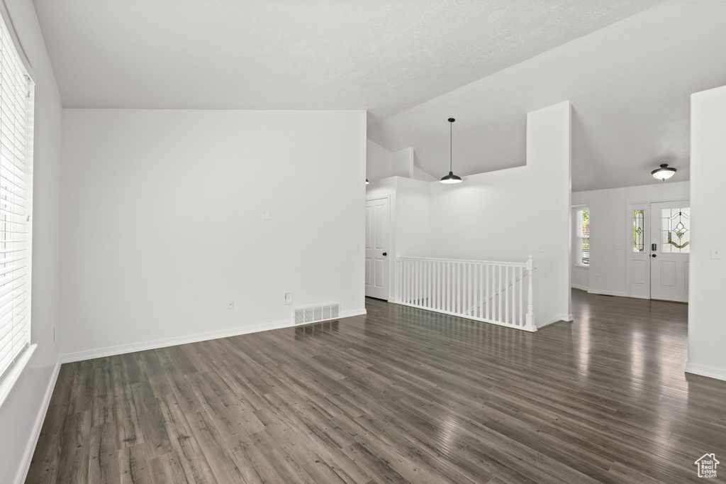 Spare room with vaulted ceiling, dark wood-type flooring, and baseboards