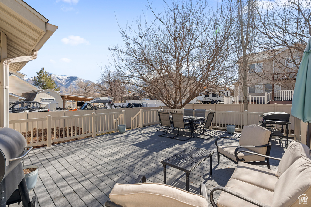 View of patio featuring outdoor dining area, outdoor lounge area, a deck with mountain view, a grill, and fence