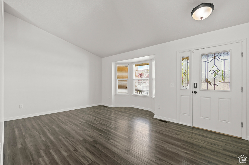 Foyer featuring lofted ceiling, dark wood-type flooring, and baseboards