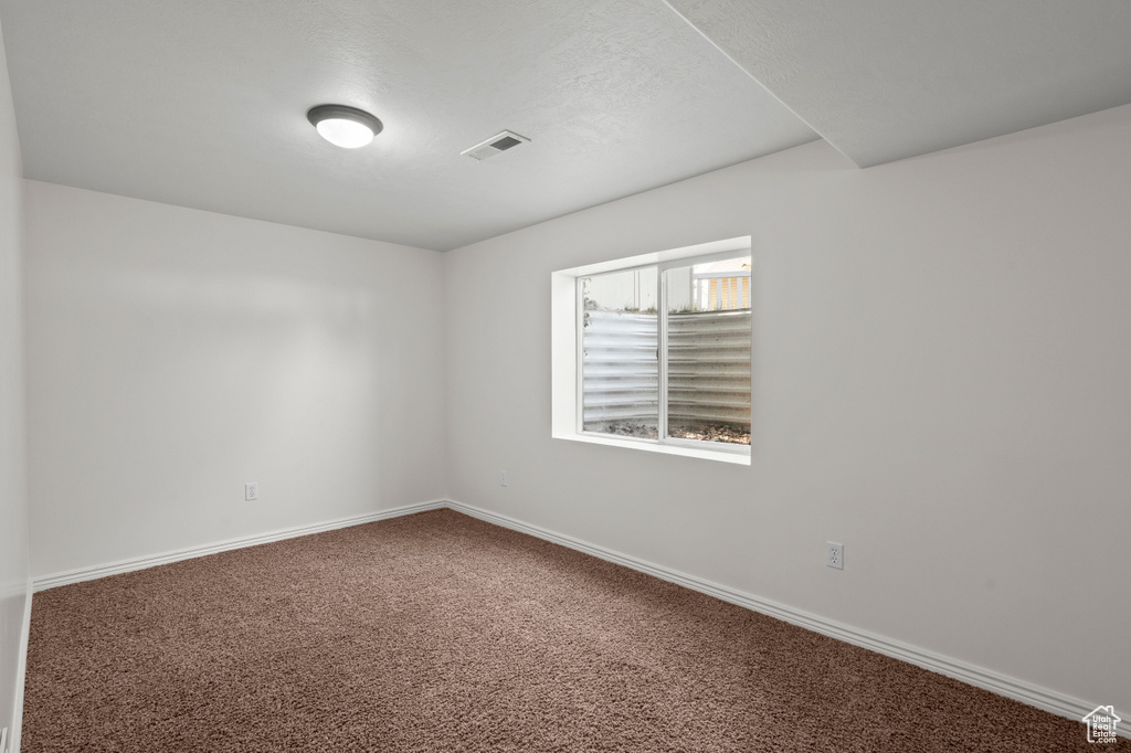 Carpeted spare room featuring baseboards