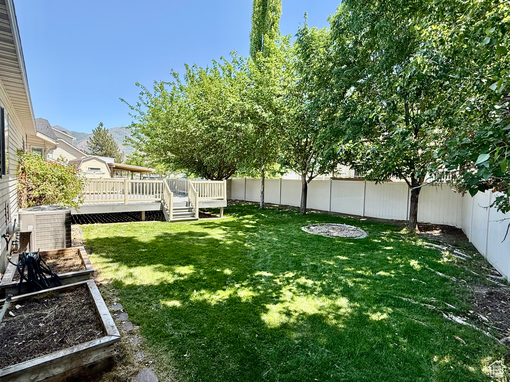 View of yard with central AC unit and a deck with mountain view