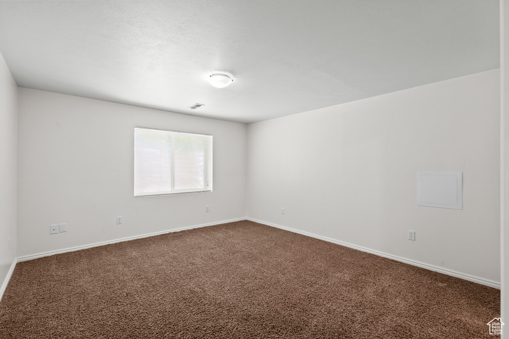 Unfurnished room featuring dark carpet and baseboards