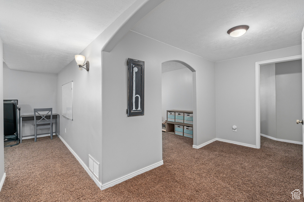 Hall featuring carpet, visible vents, arched walkways, and baseboards