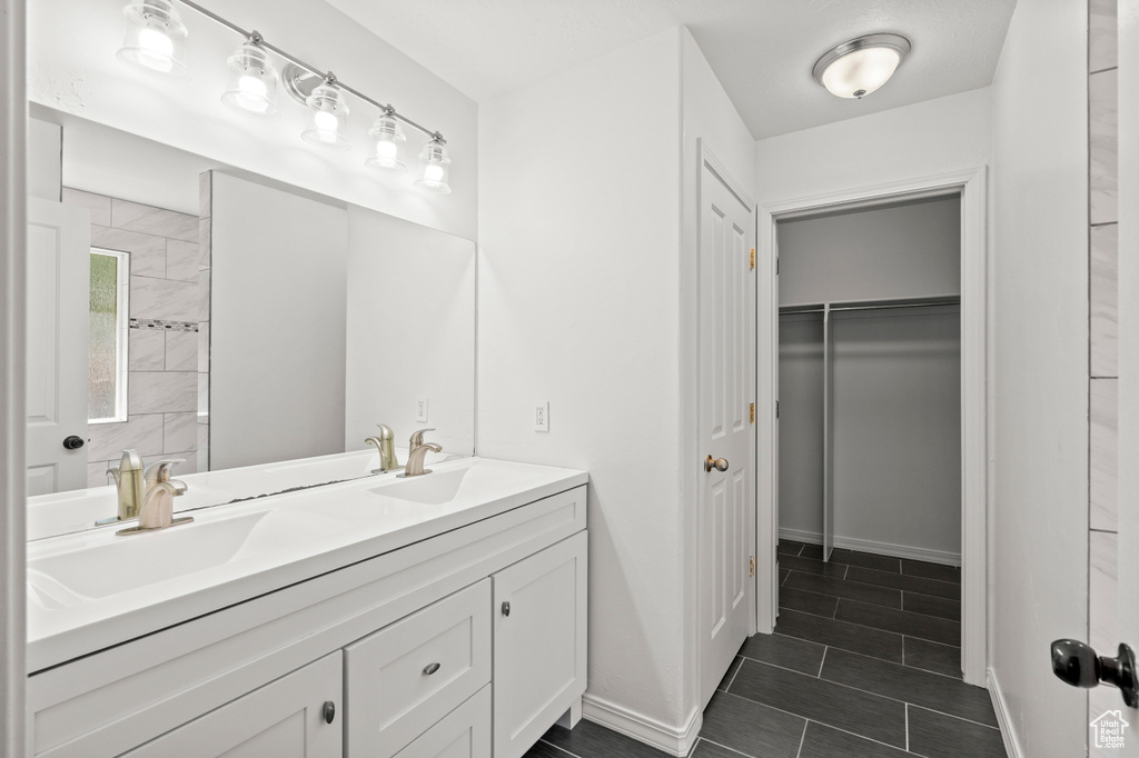 Bathroom featuring double vanity, tile patterned flooring, baseboards, and a spacious closet